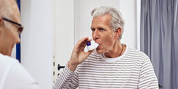COPD Untersuchung beim Arzt Ein COPD-Patient benutzt während der Untersuchung beim Arzt einen Spacer, um die Atmung zu erleichtern.